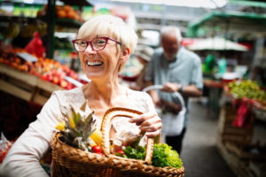 Mature Woman Buying Vegetables At Farmers Market