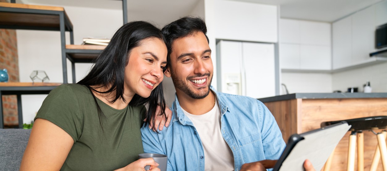 Happy Couple At Home Making A Reservation Using A Digital Tablet