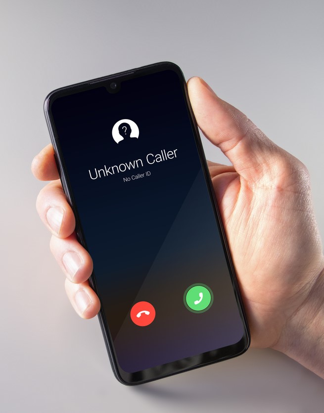 Male Hand Holding A Smartphone With Unknown Caller Displayed On Screen