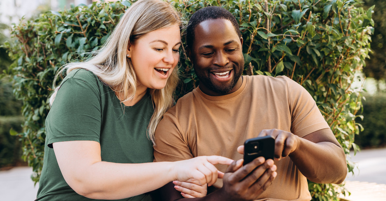 Happy multiracial couple looking at phone.